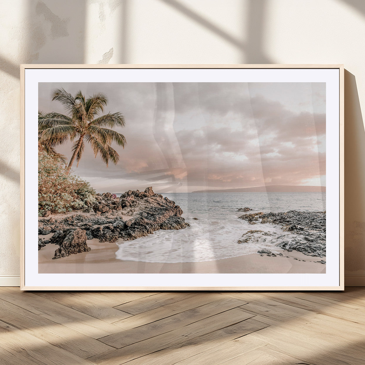 A peaceful beach scene with a palm tree and rocks, soft waves washing onto the shore under a soft pastel sky at sunset.