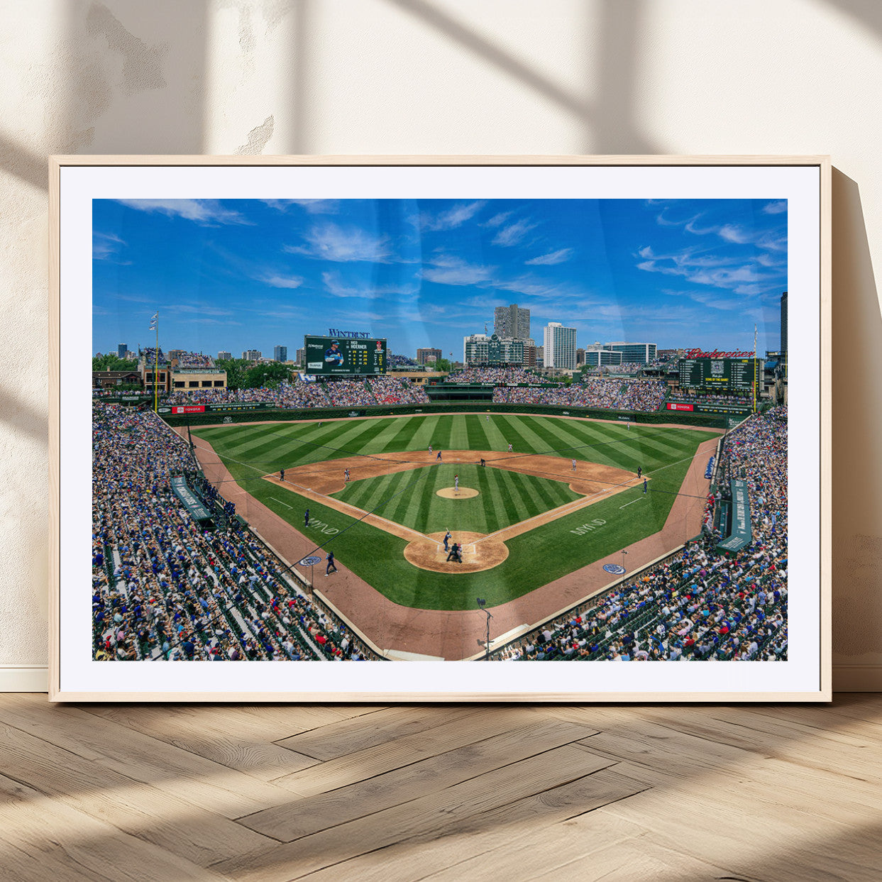 A wide-angle shot of a baseball field filled with spectators, with players on the field and the iconic Wrigley Field scoreboard in the background.