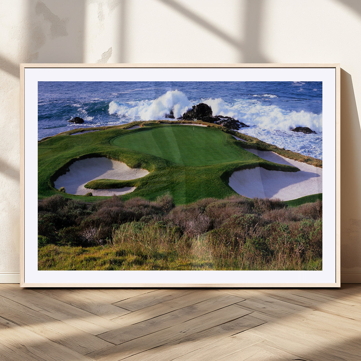 A scenic golf course located by the ocean, featuring a well-manicured green surrounded by sand traps and powerful ocean waves crashing on the shore.