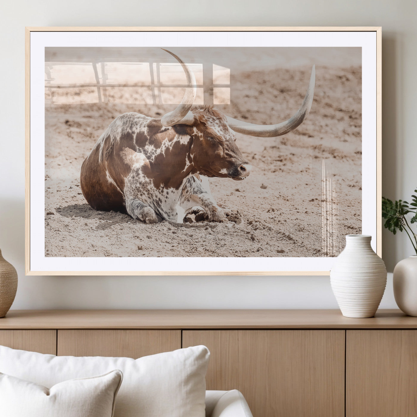 Texas Longhorn bull resting on dusty ground with warm tones, ideal for rustic western or farmhouse-themed wall decor.