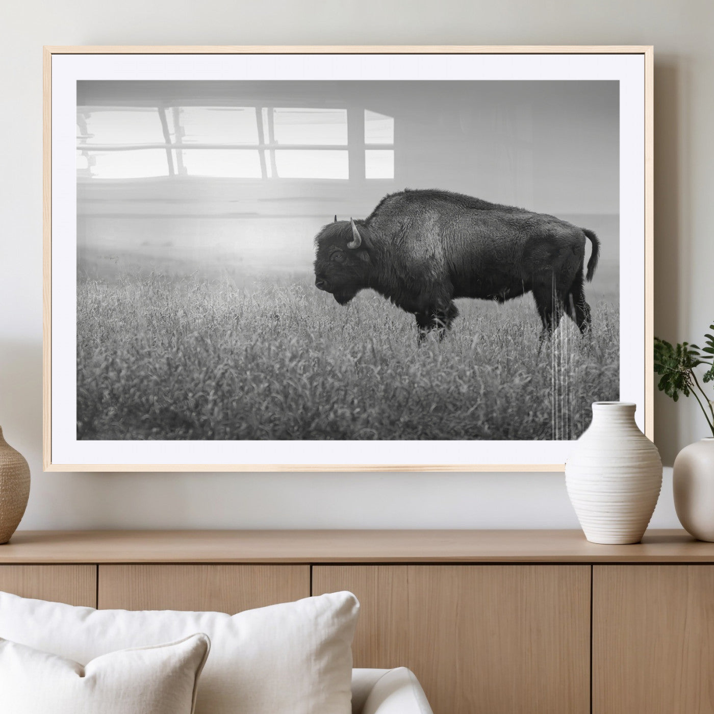 A black and white photograph of a majestic bison standing in a vast grassy prairie, evoking a sense of wilderness and strength.
