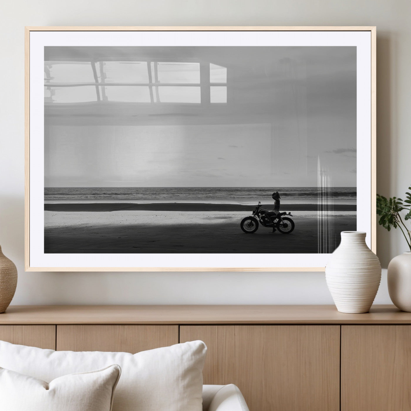 A motorcyclist on a vast beach, gazing at the ocean, capturing a moody and tranquil coastal adventure in black and white.