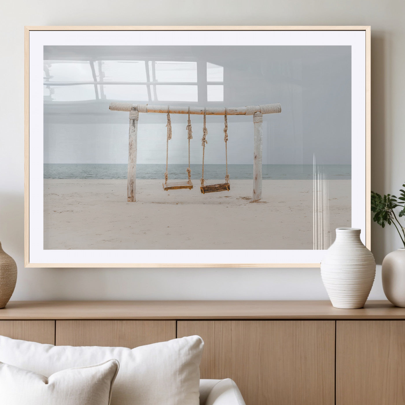 A rustic wooden beach swing stands on a serene sandy shore with an ocean horizon in the background, creating a tranquil and dreamy coastal escape.