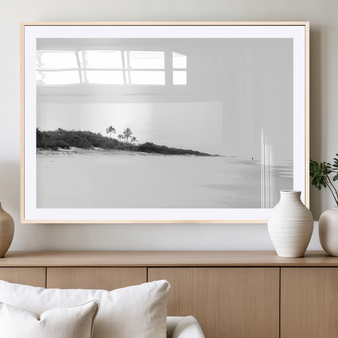 A black and white minimalist coastal scene with a vast open beach, distant palm trees, and a lone figure walking along the shoreline, evoking serenity and solitude.