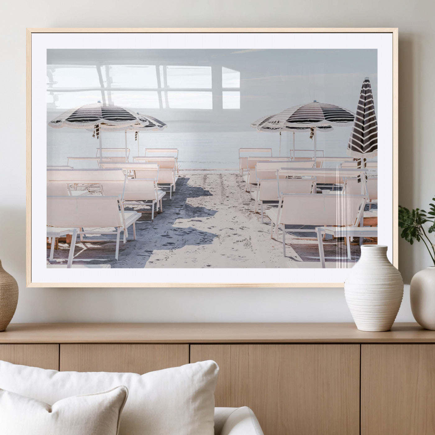A serene minimalist beach scene featuring striped umbrellas, soft pastel sand, and an elegant lounge setup, creating a tranquil and stylish coastal retreat.