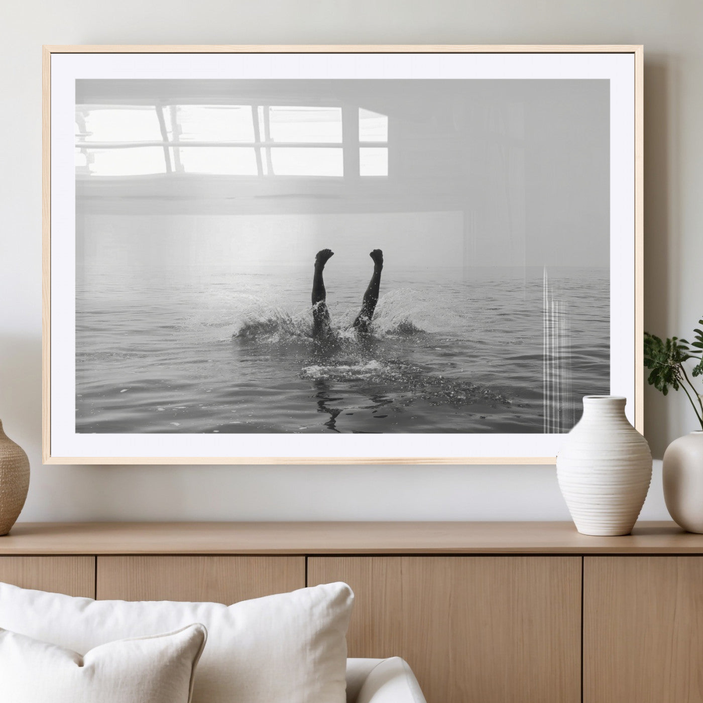 A black and white minimalist water scene capturing a playful splash as a swimmer dives upside down, creating a carefree and artistic aquatic aesthetic.