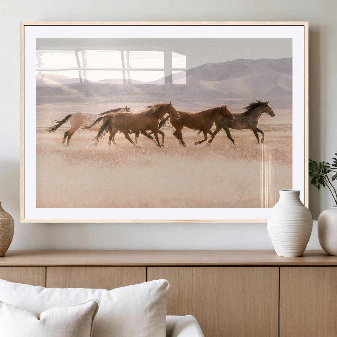 A herd of wild horses galloping through a sunlit desert plain with mountains in the background, perfect for rustic or western-themed wall decor.
