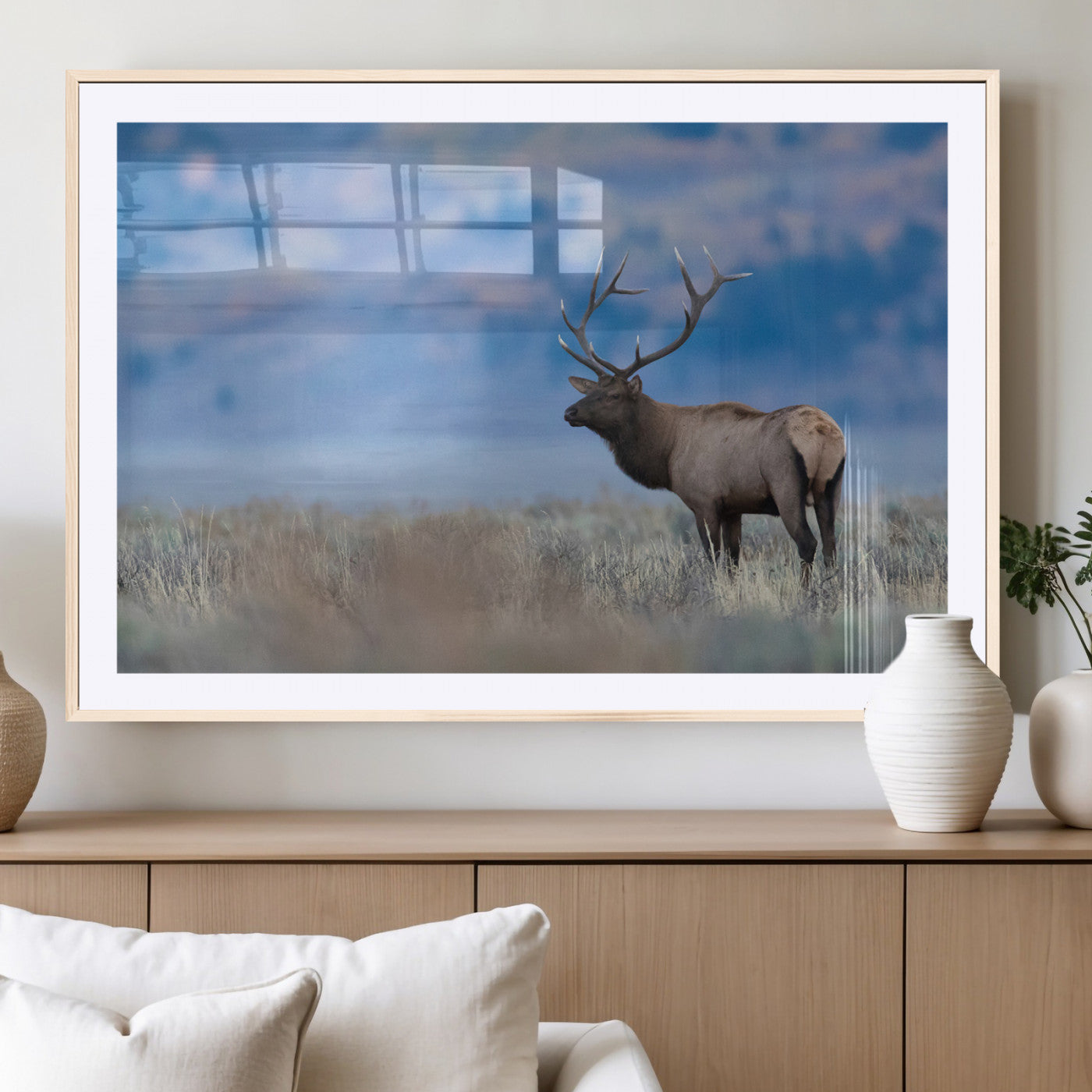 Elk with large antlers standing in open field, mountains blurred in background, perfect for rustic cabin or lodge-style decor.