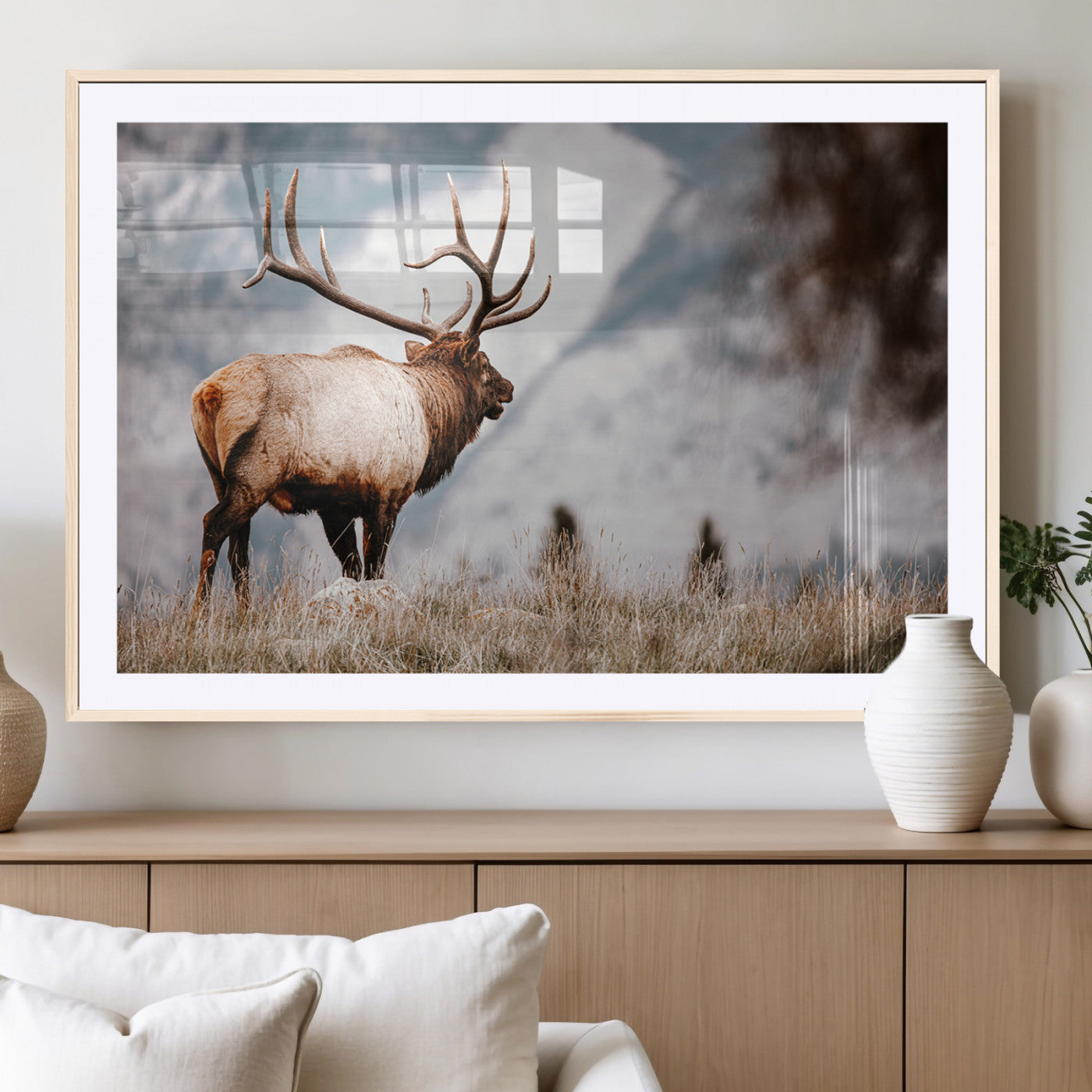 Majestic elk with large antlers standing in grass with snowy mountains in background, perfect for rustic cabin or lodge style decor.