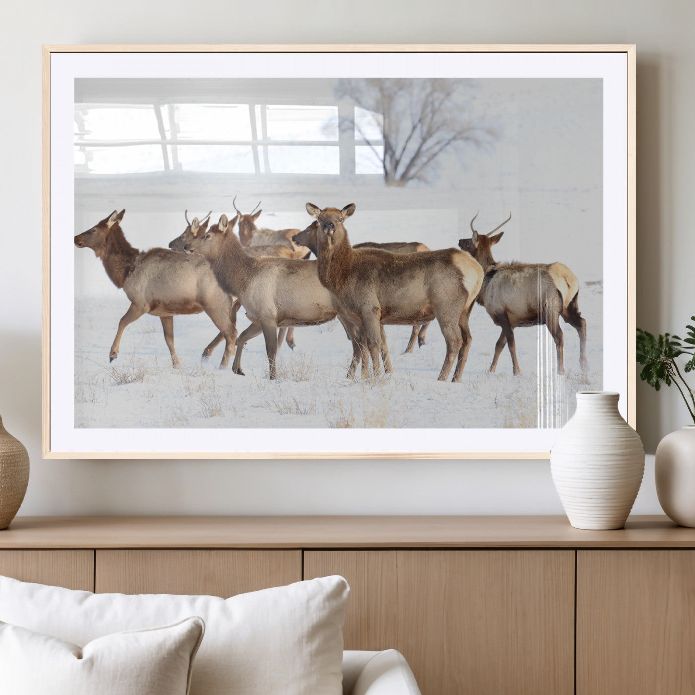 A group of elk standing on snowy terrain with a tree in the background, perfect for rustic or lodge-style winter wall decor.