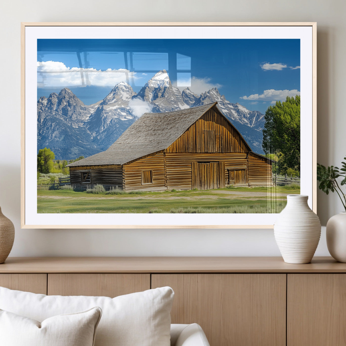 A rustic wooden barn sits in front of towering mountain peaks under a clear blue sky, perfect for farmhouse or cabin style interiors.