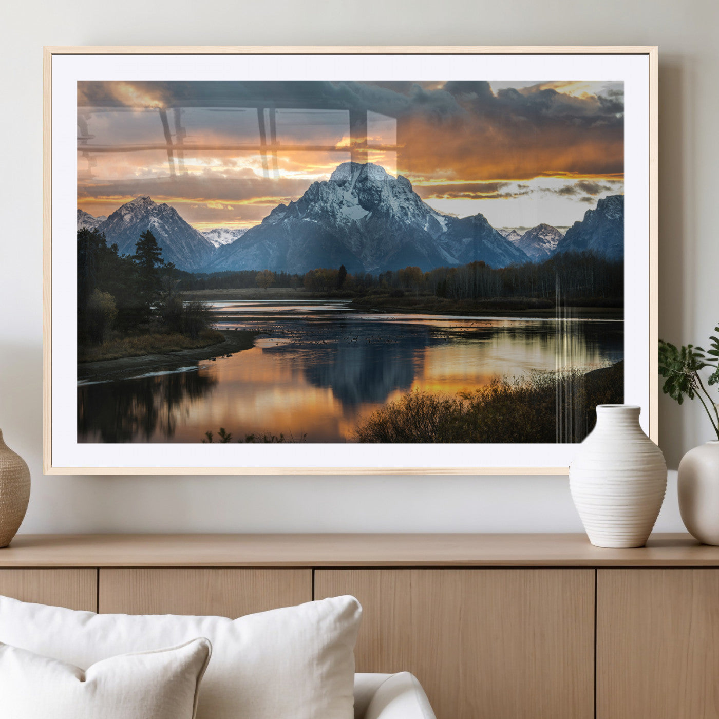 Snow-capped mountains reflecting in a calm lake at sunset, with a dramatic golden sky creating a breathtaking wilderness scene.