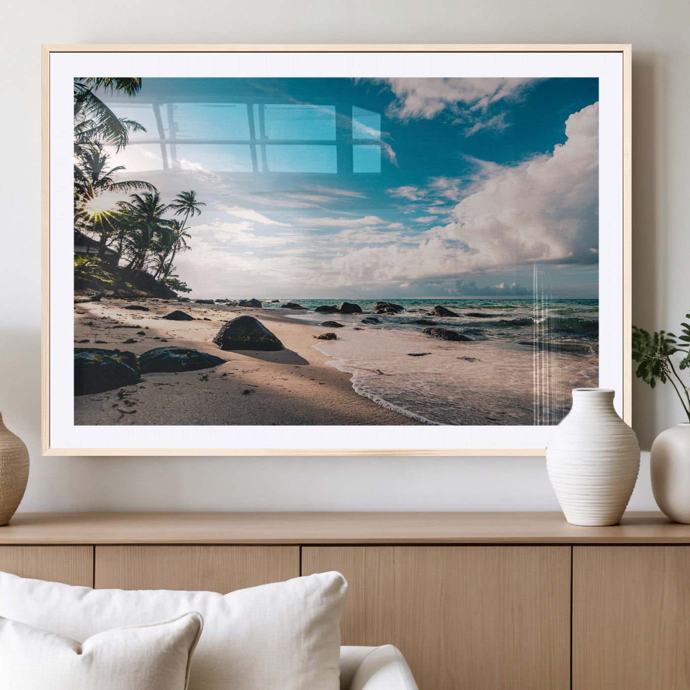 Scenic tropical beach with palm trees, ocean waves, and rocky shoreline under a bright blue sky, creating a serene coastal vibe.