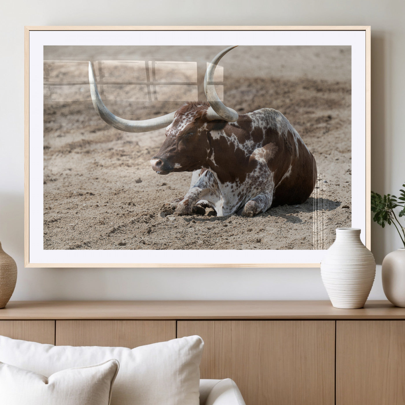 Texas Longhorn resting on sandy ground with large curved horns, capturing a rustic Western aesthetic perfect for farmhouse-style wall art.