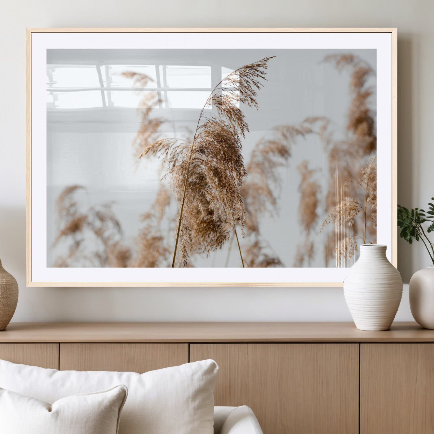 Close-up of pampas grass swaying in the wind against a soft white sky, creating a neutral and minimalist botanical aesthetic.