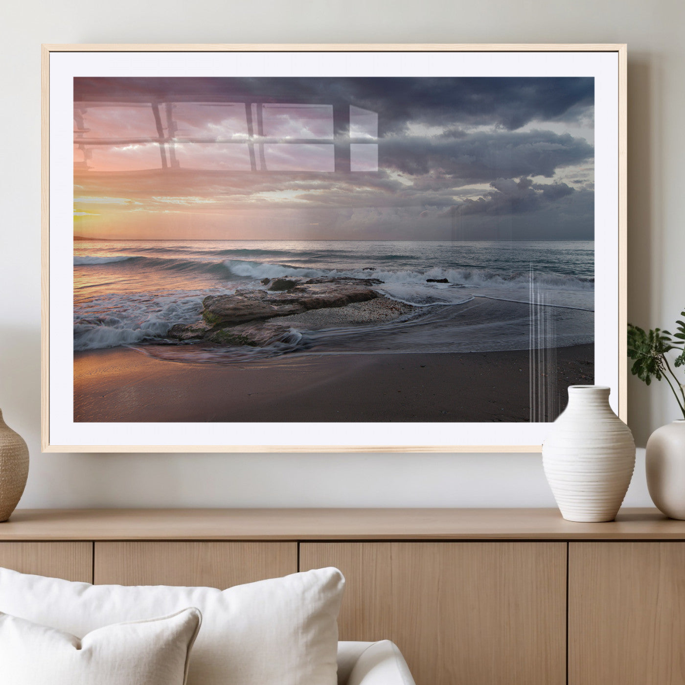 Dramatic sunset over a rocky shoreline with ocean waves gently reaching the sandy beach, creating a serene and coastal atmosphere.