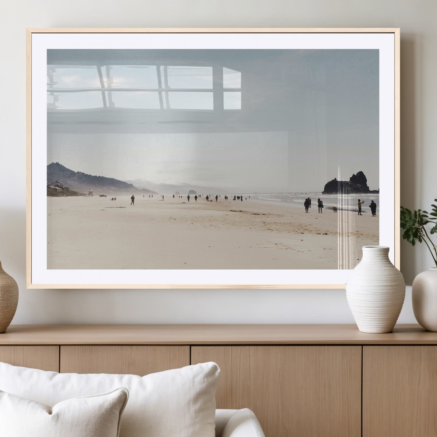 A serene beach with soft sand, misty mountains, and scattered people walking along the shoreline, creating a peaceful coastal landscape.