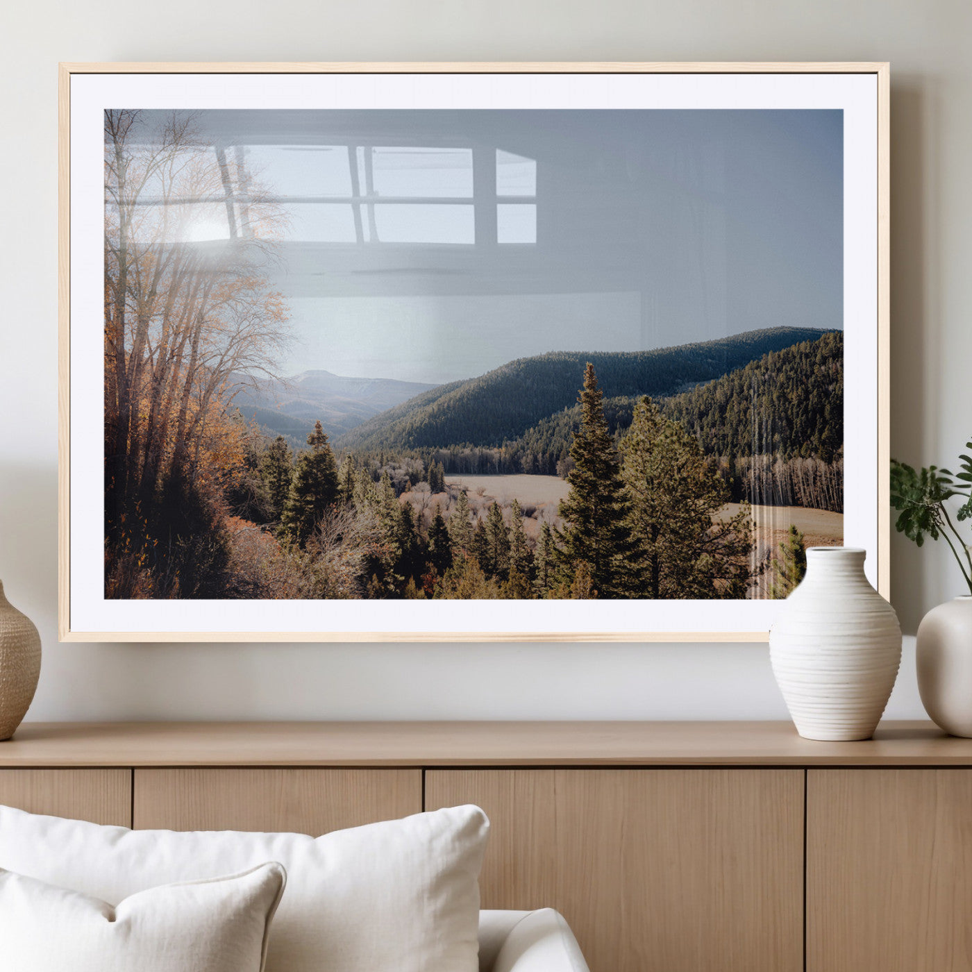 A scenic mountain valley with pine trees and autumn foliage under a clear sky, bathed in golden sunlight, creating a peaceful and rustic landscape.