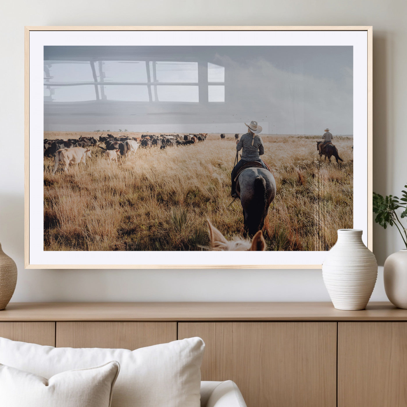 A cowboy and cowgirl on horseback herding cattle through golden grasslands, capturing a rustic and authentic Western ranch lifestyle.