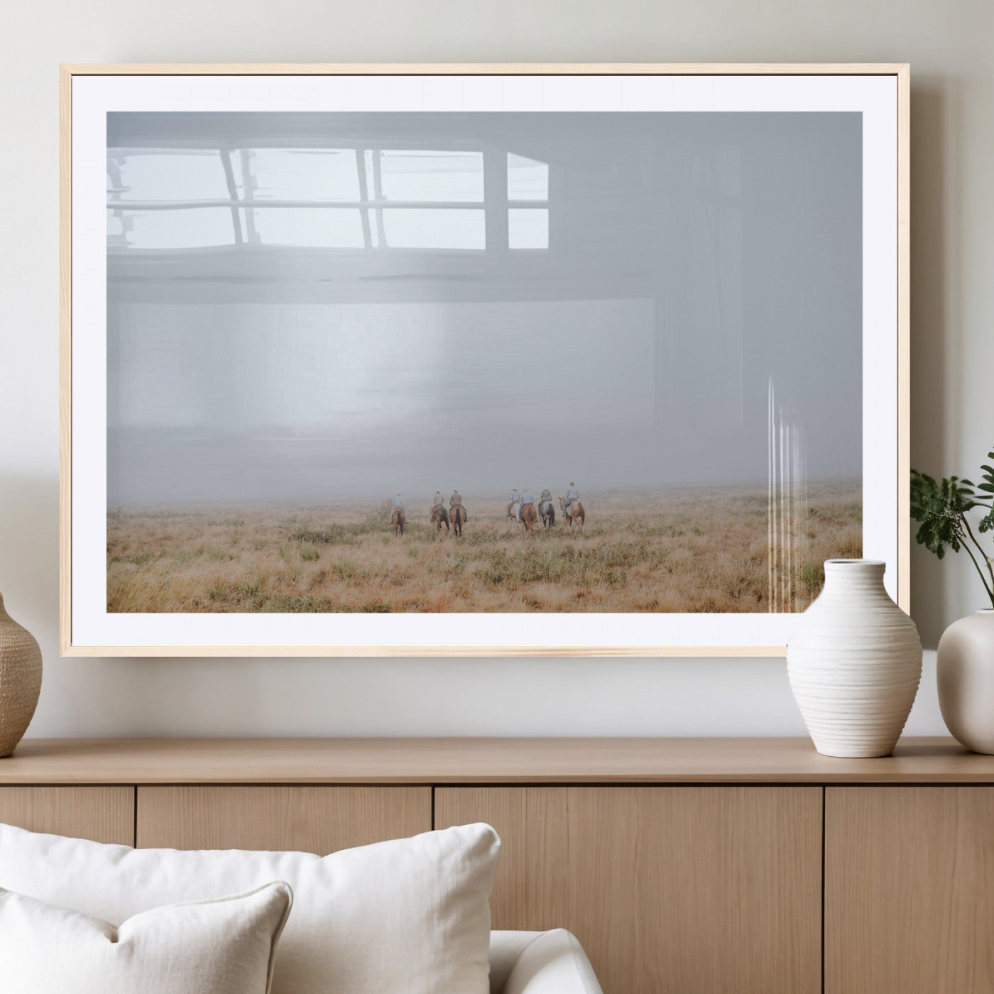 A group of horseback riders moving through a fog-shrouded field, evoking a calm Western scene with golden grasses and soft horizons.