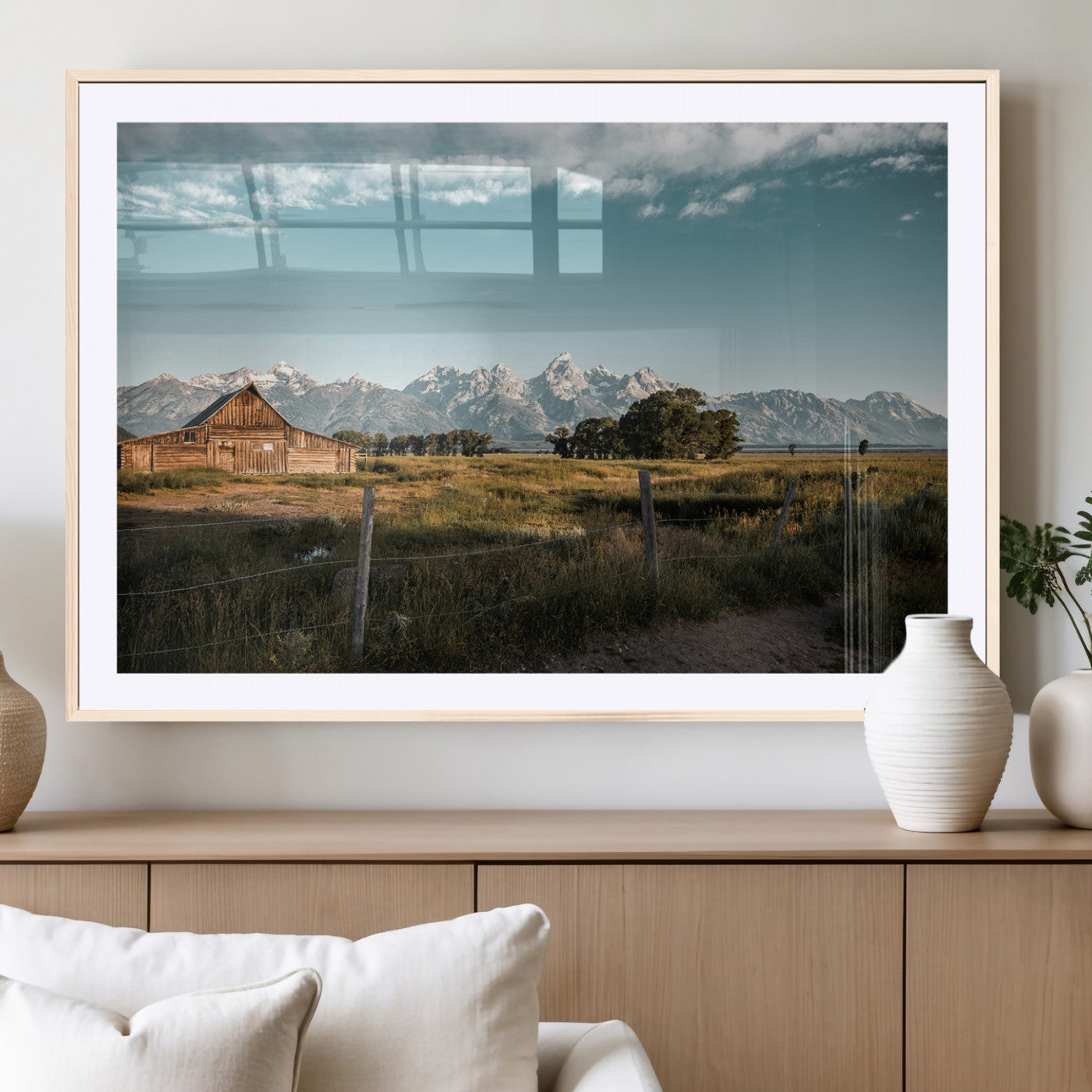 A rustic farmhouse with a wooden barn set against majestic mountain peaks under a soft blue sky, evoking peaceful countryside charm.