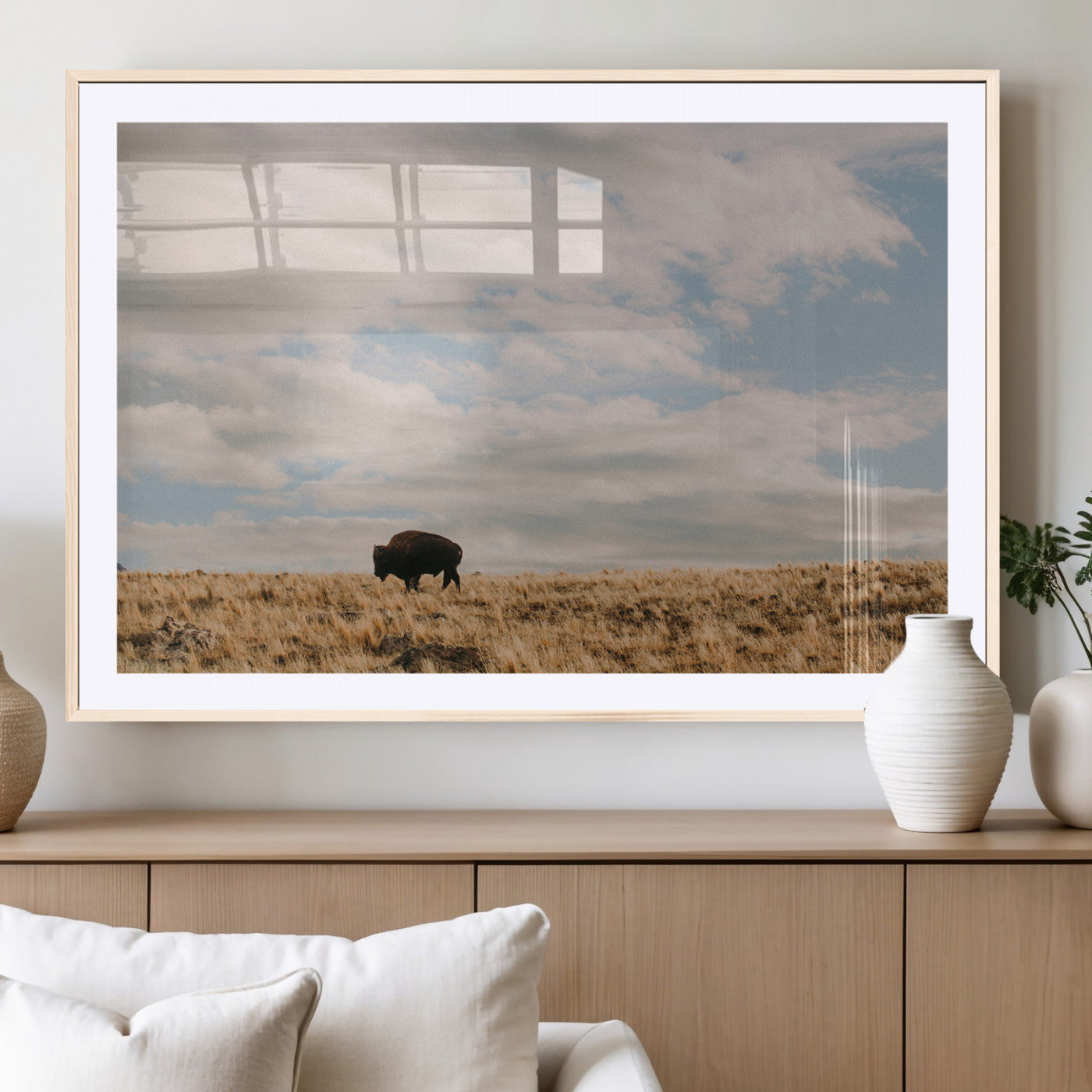A solitary bison walking across a golden prairie under a vast, cloud-filled sky, evoking a peaceful, rustic western landscape for home decor.