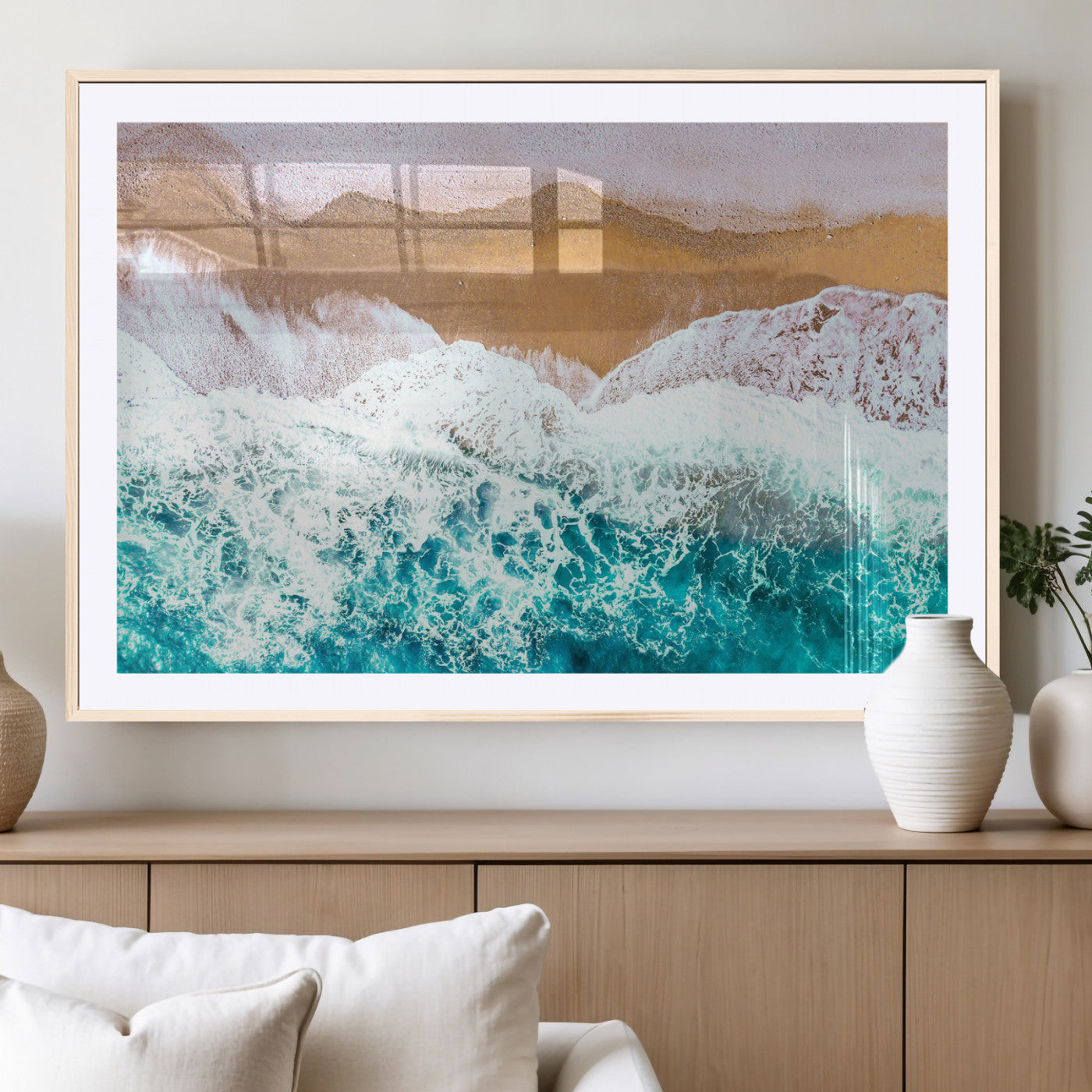 Aerial view of ocean waves crashing onto a sandy beach, with turquoise water and foamy white surf, creating a serene coastal aesthetic for home decor.