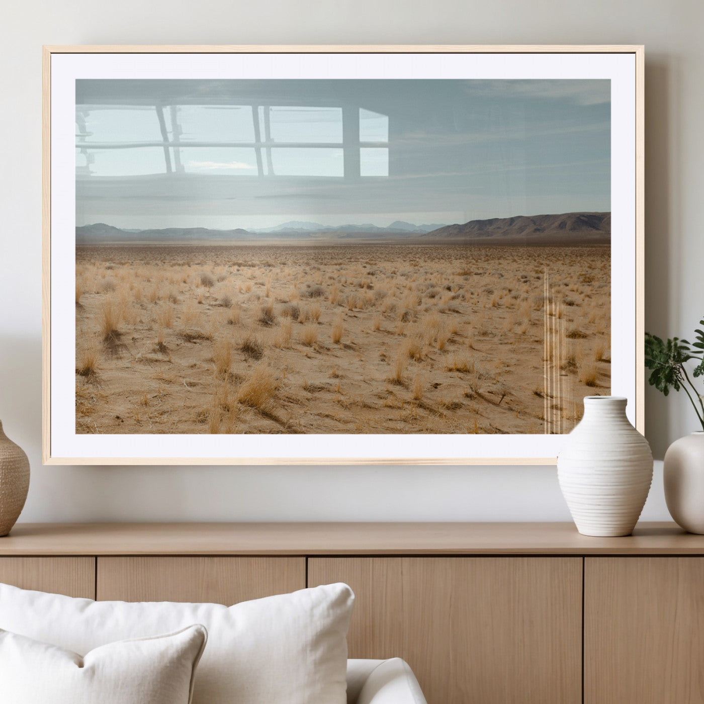 Expansive desert landscape with scattered dry grass and distant mountain range under a pale blue sky – Wall Art Canvas Print.