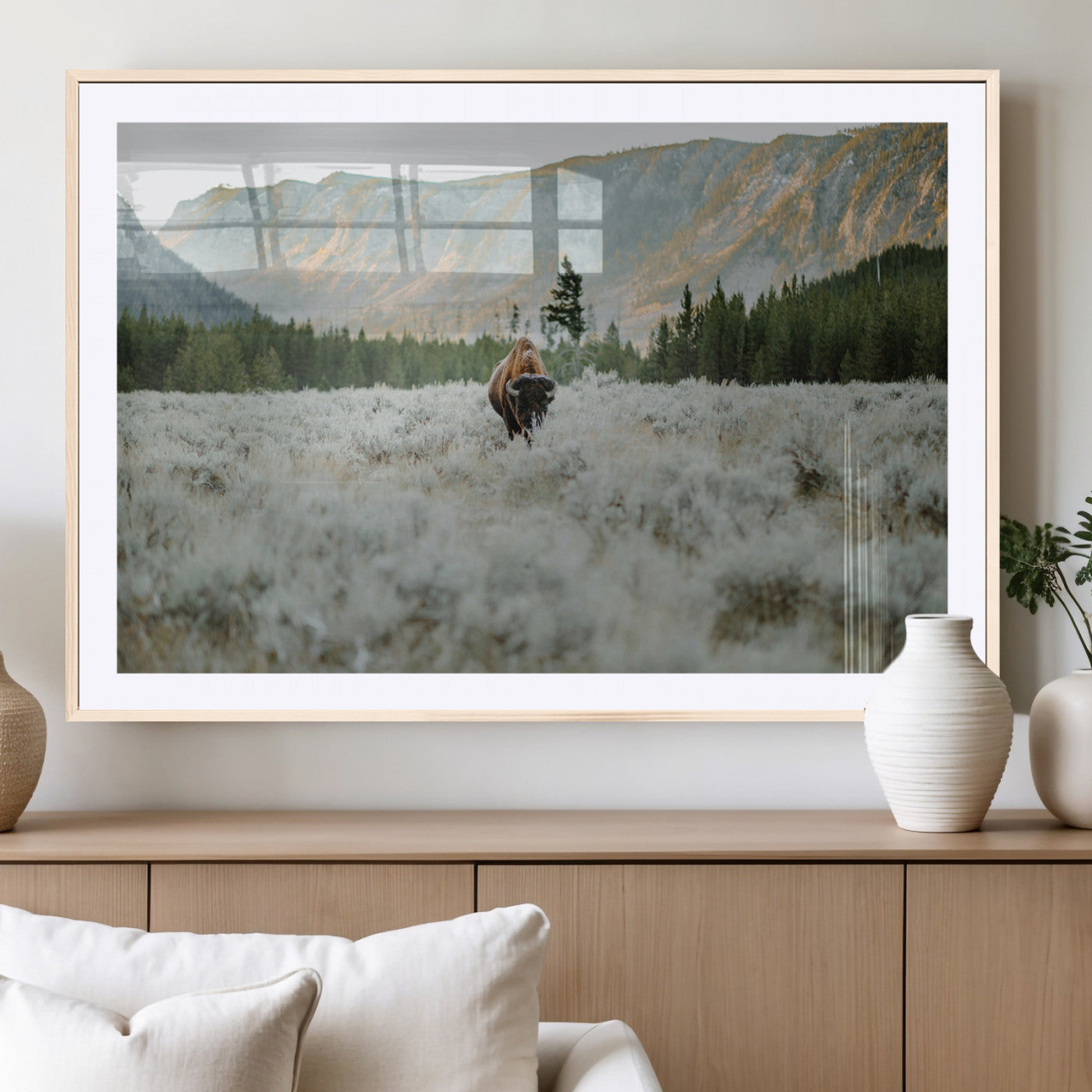 Lone bison standing in a frosted sagebrush field with a pine forest and rugged mountain range in the background under soft morning light – Wall Art Canvas Print.