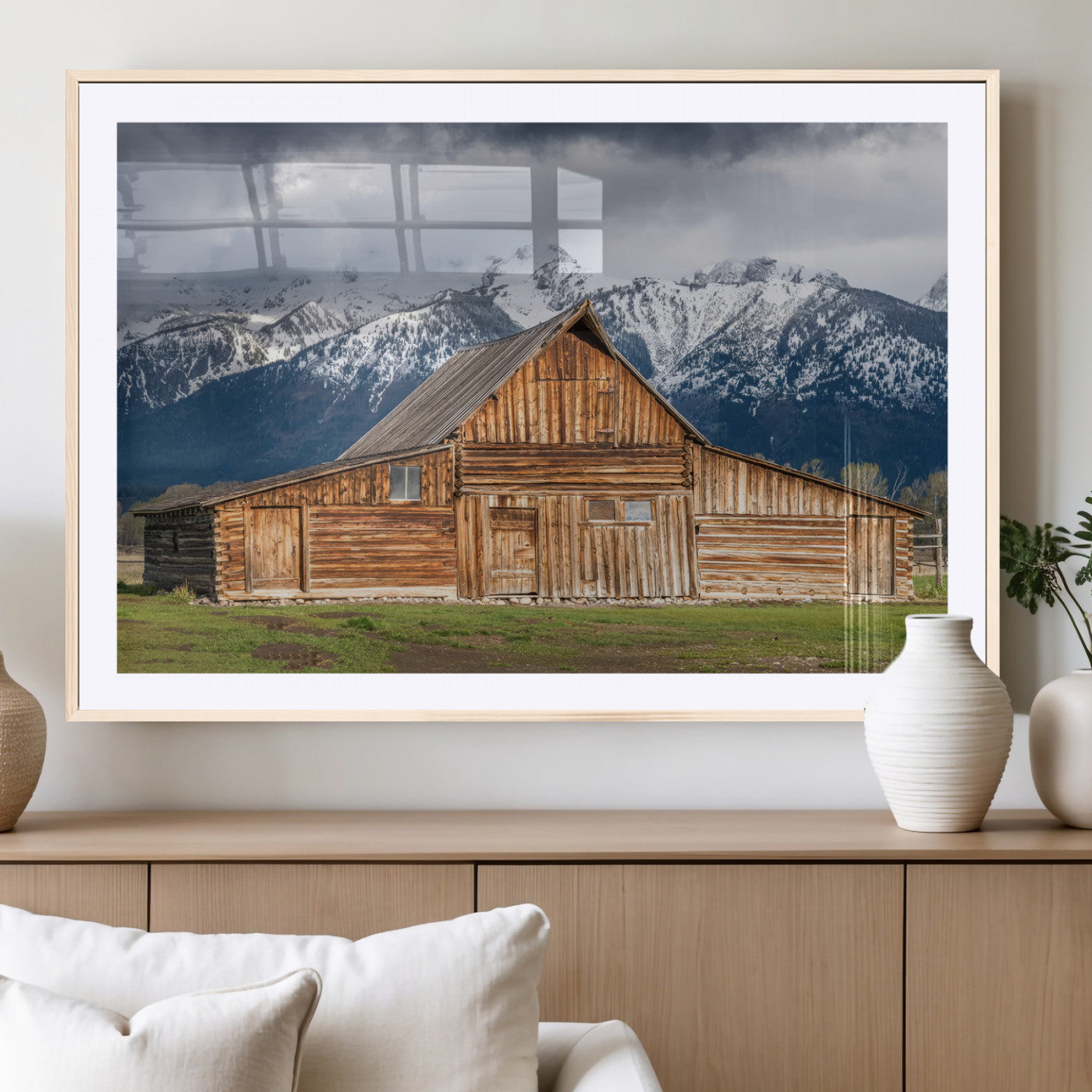 A stunning wall art canvas print featuring a rustic wooden barn set against a backdrop of snow-capped mountains under a dramatic cloudy sky, perfect for adding a touch of rural charm to any space.