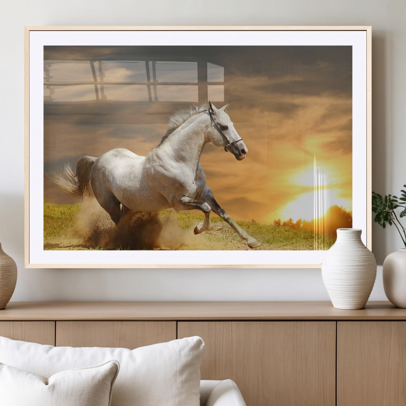 A powerful white horse galloping through the field at sunset, with the golden light illuminating its mane and the vibrant sky in the background.