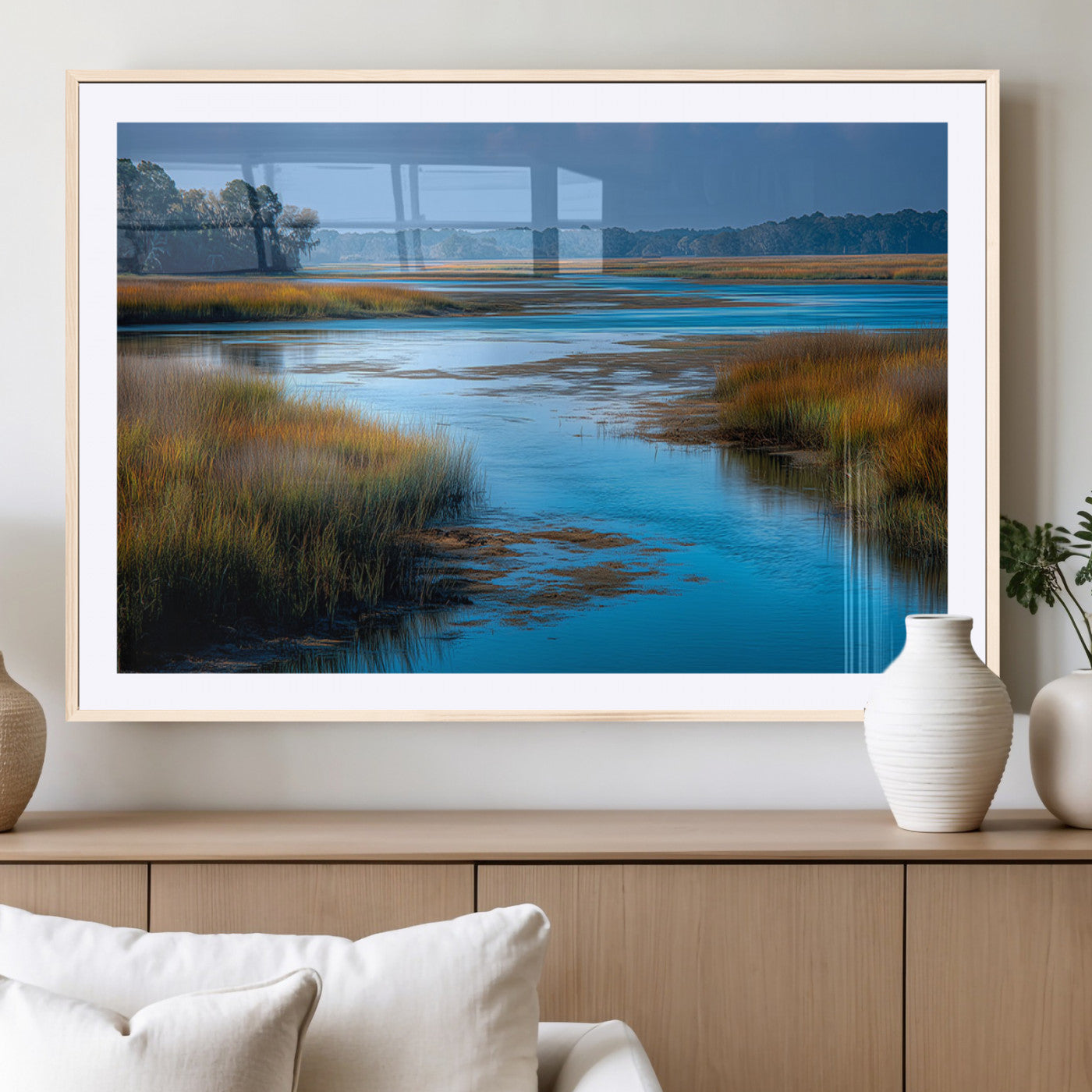 A peaceful marshland scene with calm blue water reflecting the surrounding grasses and trees, capturing the beauty of nature in a serene landscape.