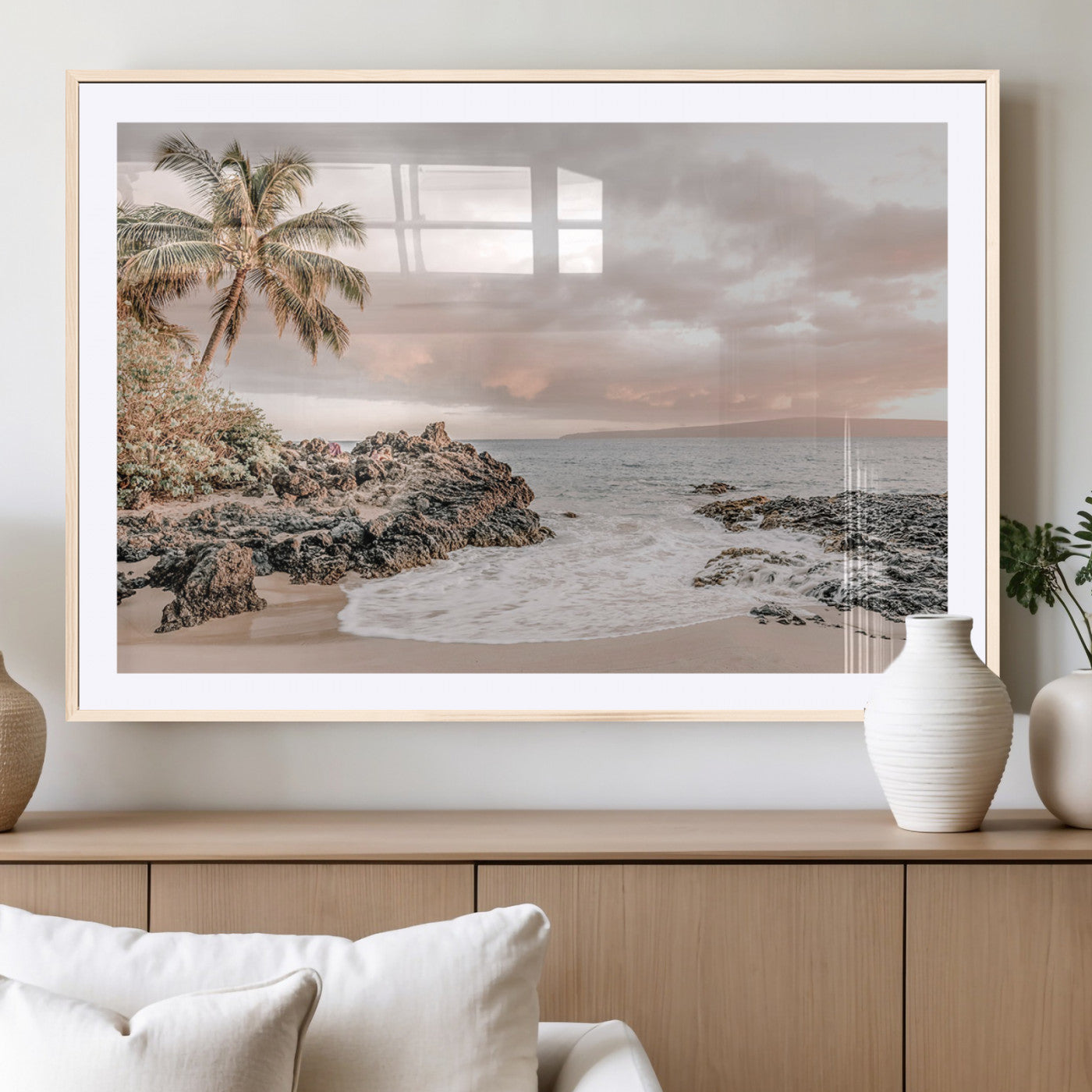 A peaceful beach scene with a palm tree and rocks, soft waves washing onto the shore under a soft pastel sky at sunset.