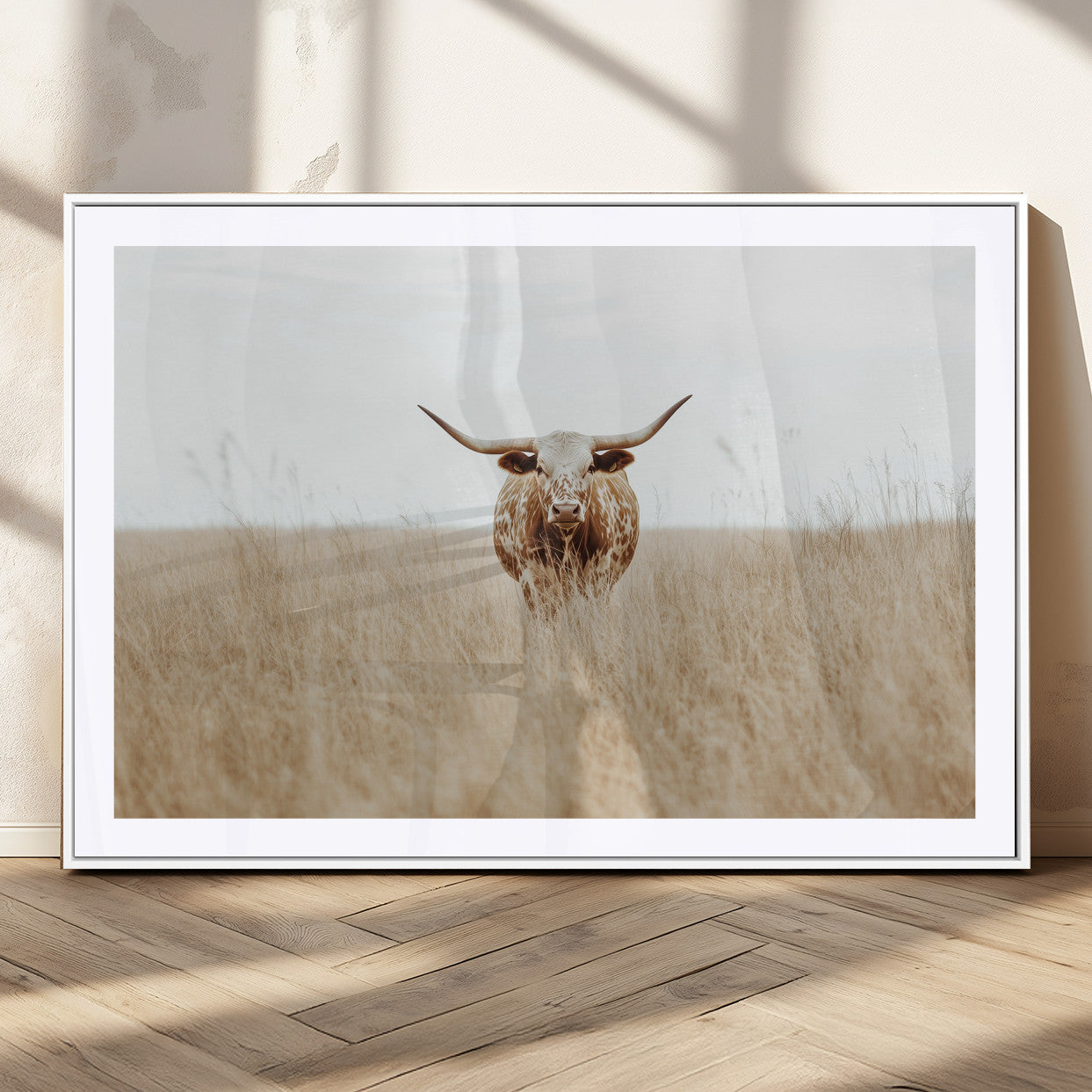 Texas Longhorn bull standing alone in dry grass with neutral tones, ideal for rustic western or cowboy-themed wall decor.