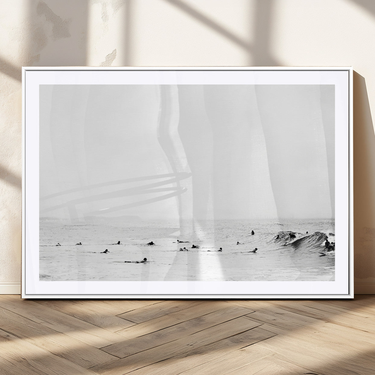 A group of surfers floating in the ocean, waiting for waves under a vast, moody sky, captured in black and white.