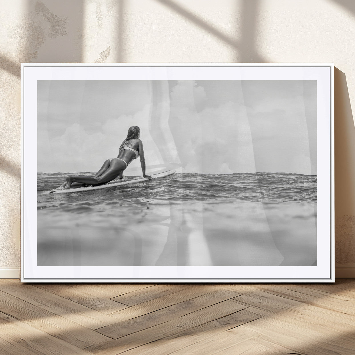 A black and white ocean scene featuring a surfer girl waiting on her board, gazing at the horizon, capturing a tranquil and adventurous coastal moment.
