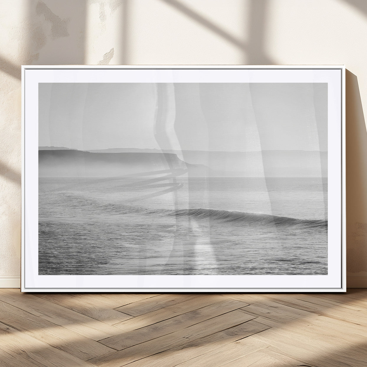 A black and white minimalist seascape featuring soft rolling waves and misty distant cliffs, creating a serene and timeless coastal atmosphere.