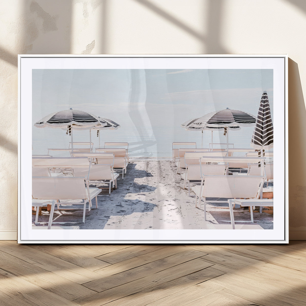 A serene minimalist beach scene featuring striped umbrellas, soft pastel sand, and an elegant lounge setup, creating a tranquil and stylish coastal retreat.