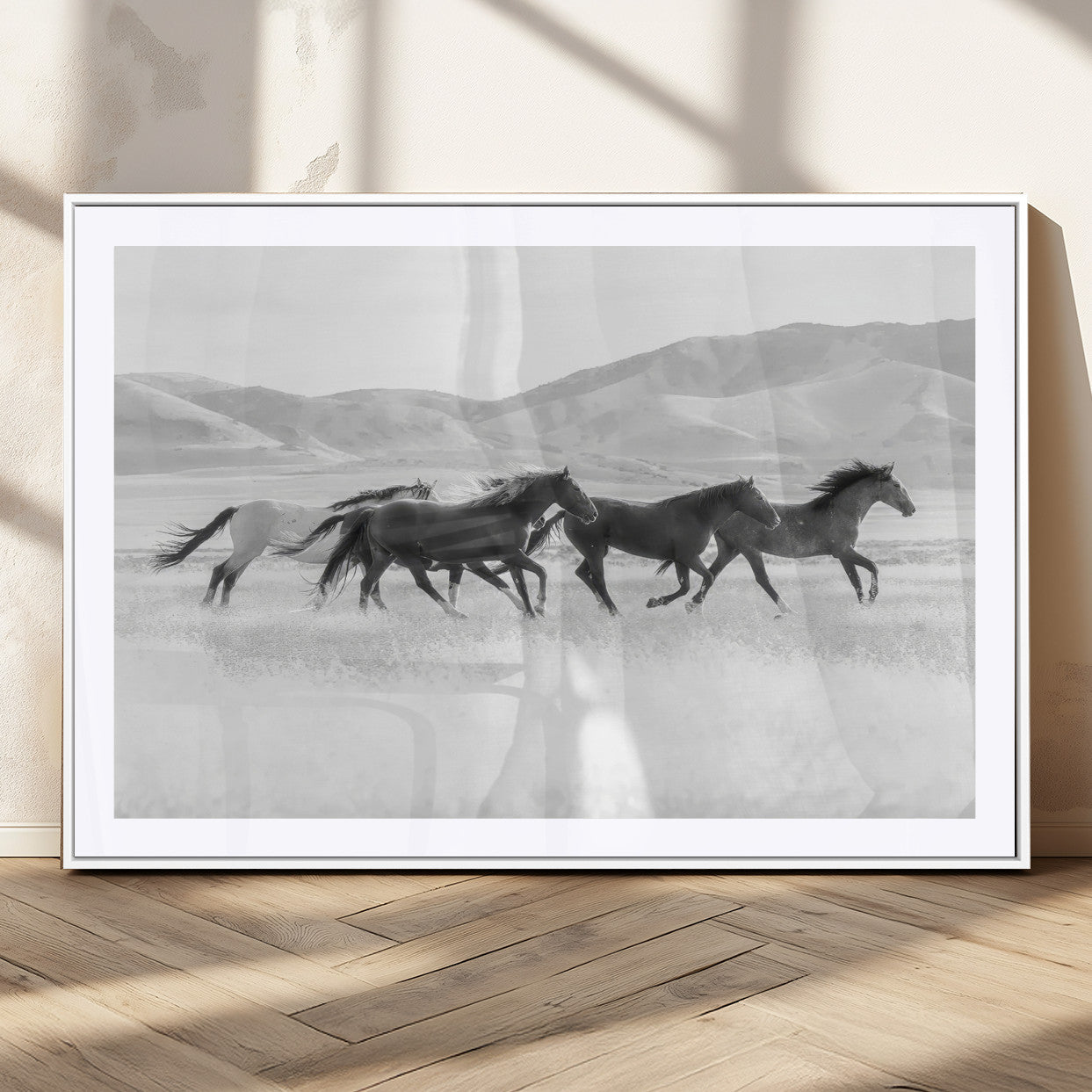 A black and white image of wild horses running freely across an open grassland, capturing the power and beauty of untamed nature in a rustic western setting.