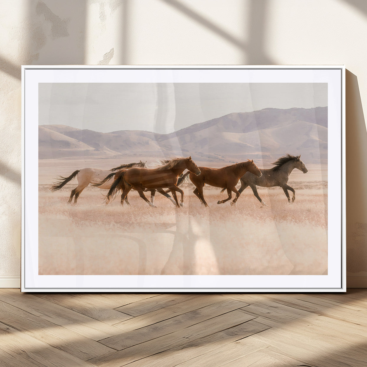 A herd of wild horses galloping through a sunlit desert plain with mountains in the background, perfect for rustic or western-themed wall decor.