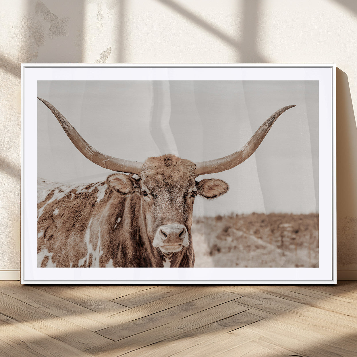 A longhorn cow in soft beige desert tones, standing calmly in open land, perfect for neutral western or rustic farmhouse interiors.