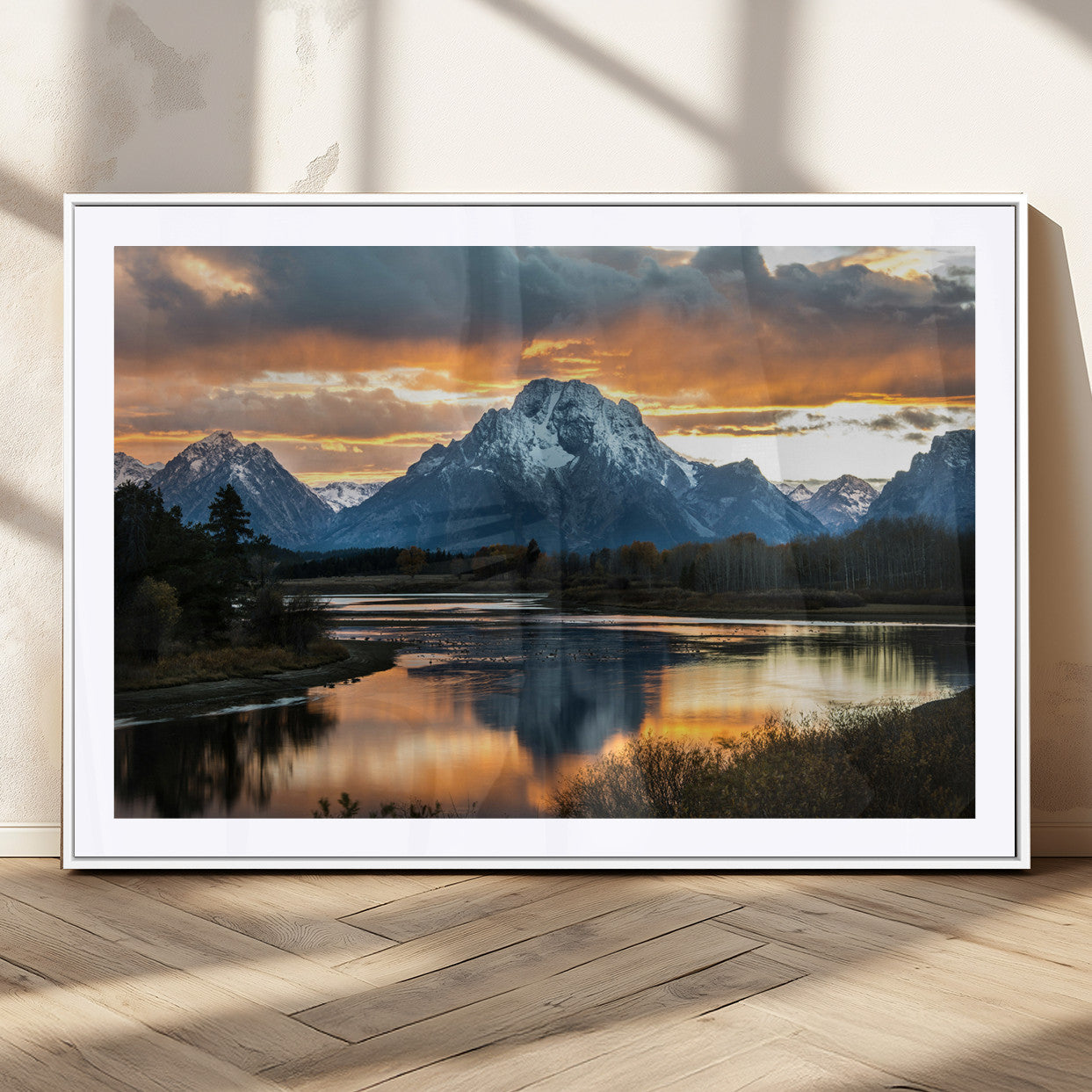 Snow-capped mountains reflecting in a calm lake at sunset, with a dramatic golden sky creating a breathtaking wilderness scene.