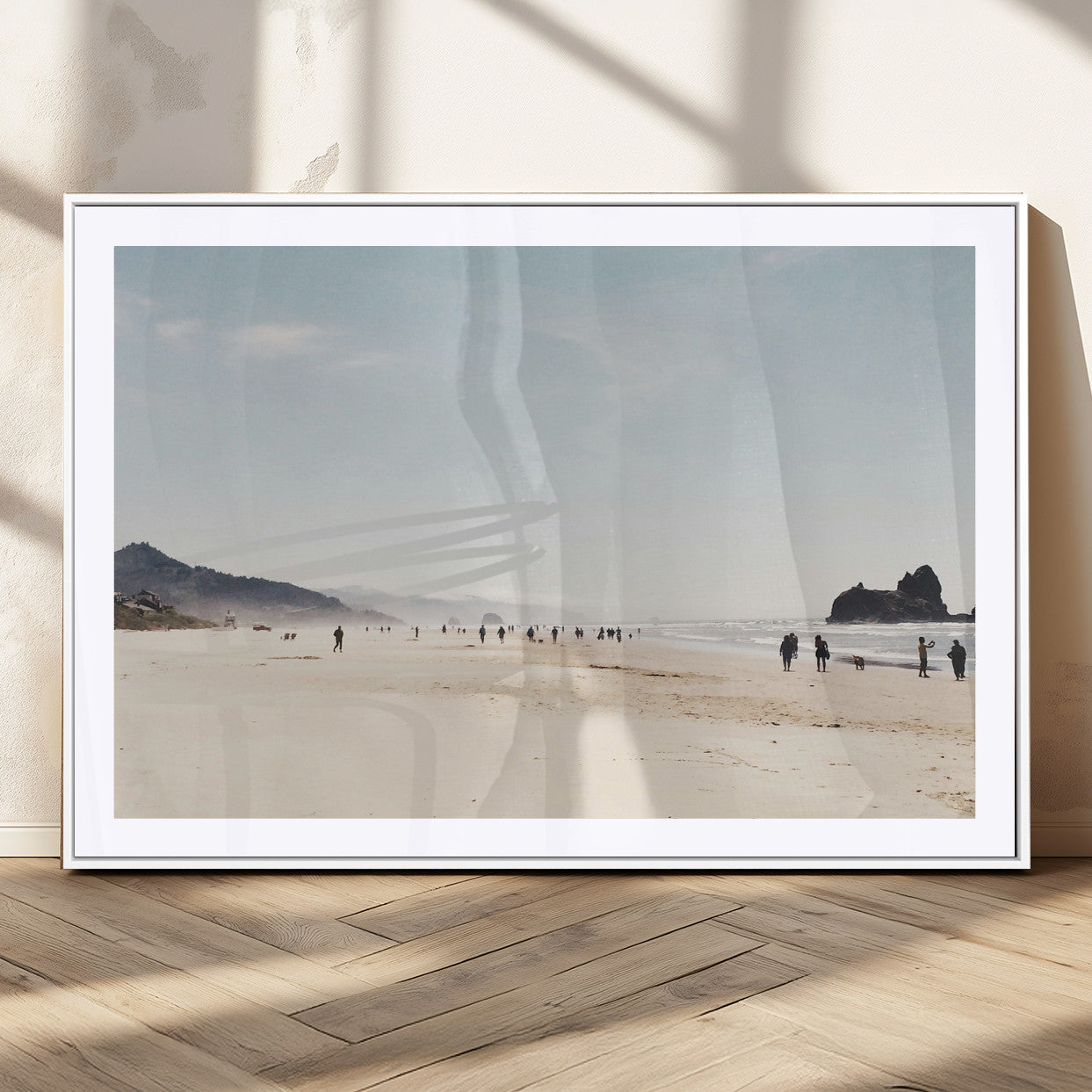 A serene beach with soft sand, misty mountains, and scattered people walking along the shoreline, creating a peaceful coastal landscape.