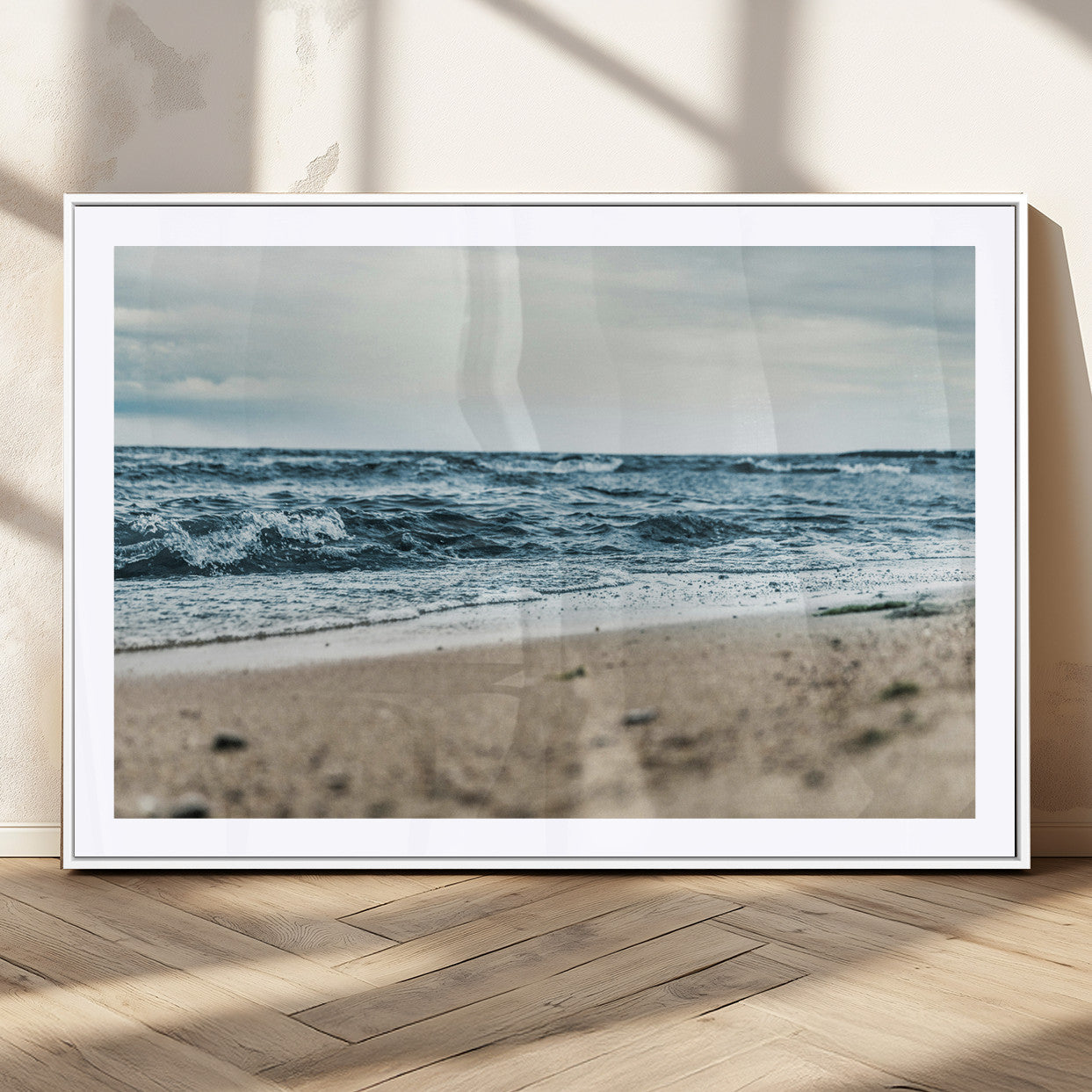 A moody ocean scene with gentle waves washing onto a sandy beach under a cloudy sky, creating a peaceful and coastal atmosphere.