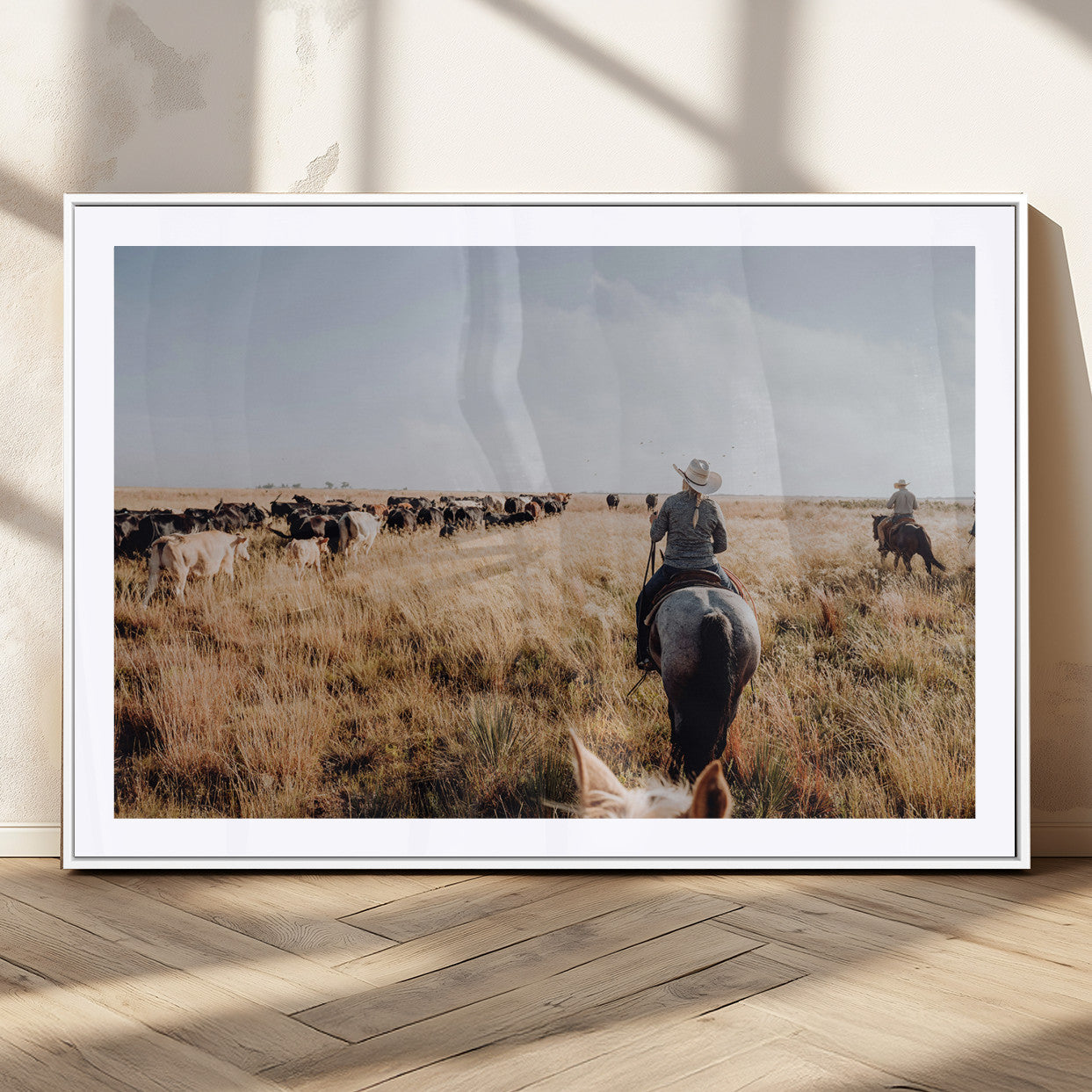 A cowboy and cowgirl on horseback herding cattle through golden grasslands, capturing a rustic and authentic Western ranch lifestyle.