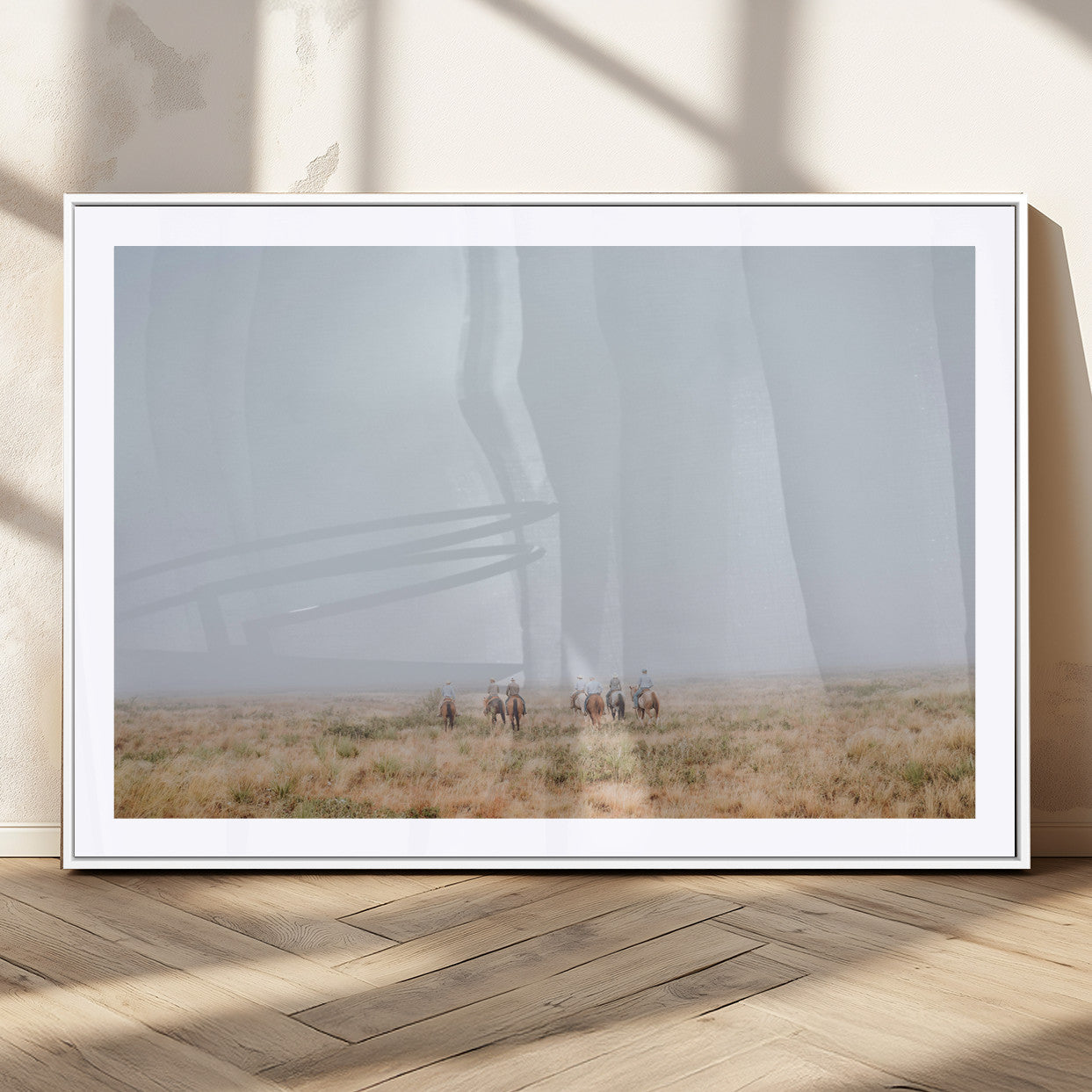 A group of horseback riders moving through a fog-shrouded field, evoking a calm Western scene with golden grasses and soft horizons.