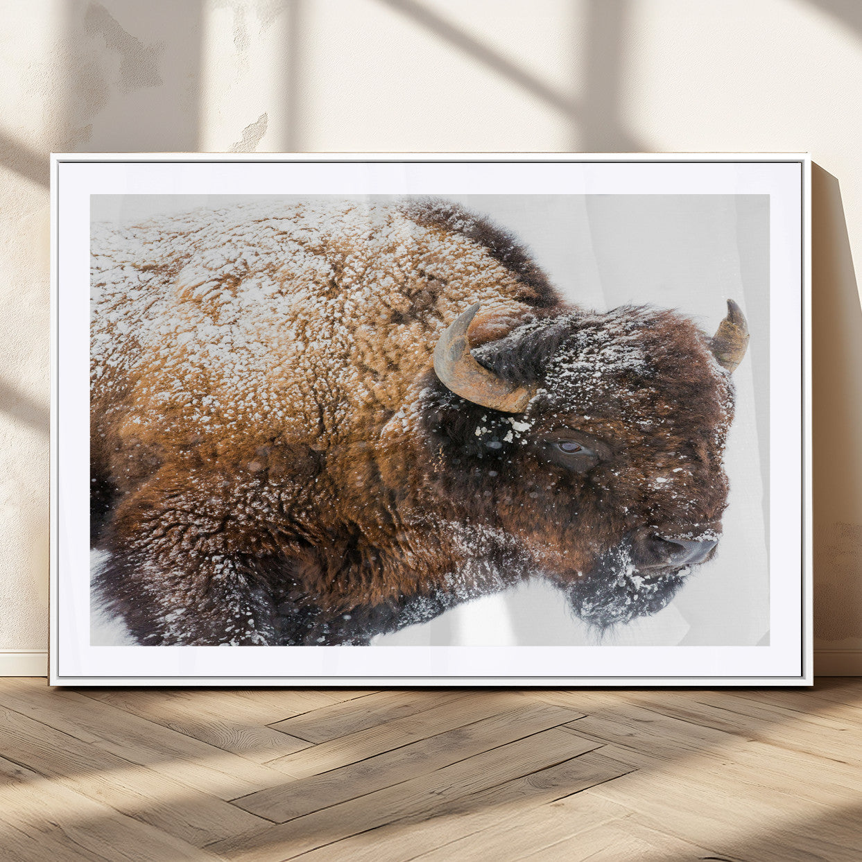 Close-up photograph of a bison covered in snow, highlighting its thick fur and powerful presence, set against a white winter backdrop, ideal for rustic decor.
