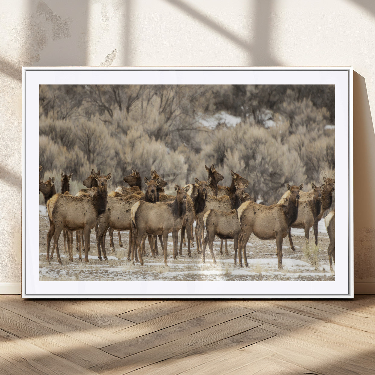 A stunning wall art canvas print featuring a large herd of elk standing together in a natural winter landscape with muted earthy tones and soft background foliage, perfect for rustic or nature-inspired home decor.