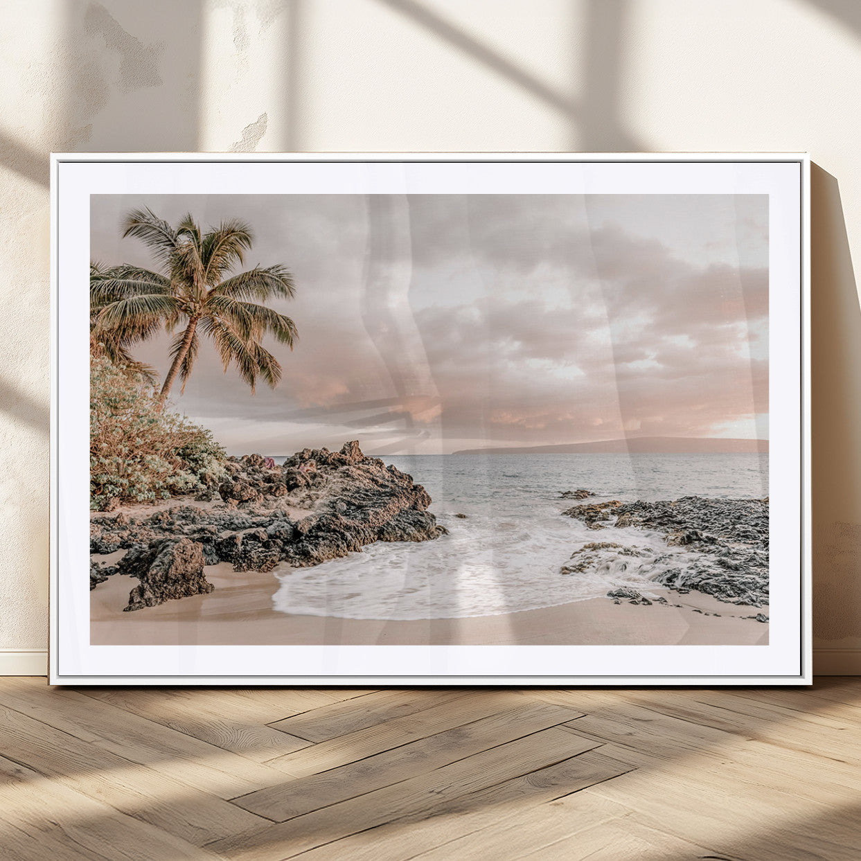 A peaceful beach scene with a palm tree and rocks, soft waves washing onto the shore under a soft pastel sky at sunset.
