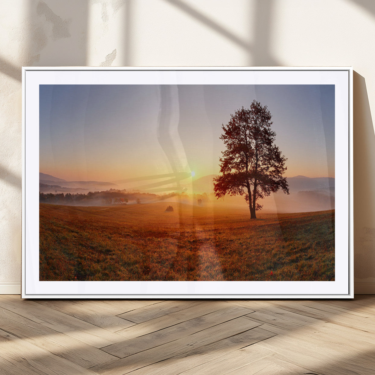 A tranquil landscape at sunrise with a mist-covered field and a lone tree, creating a peaceful and natural atmosphere.